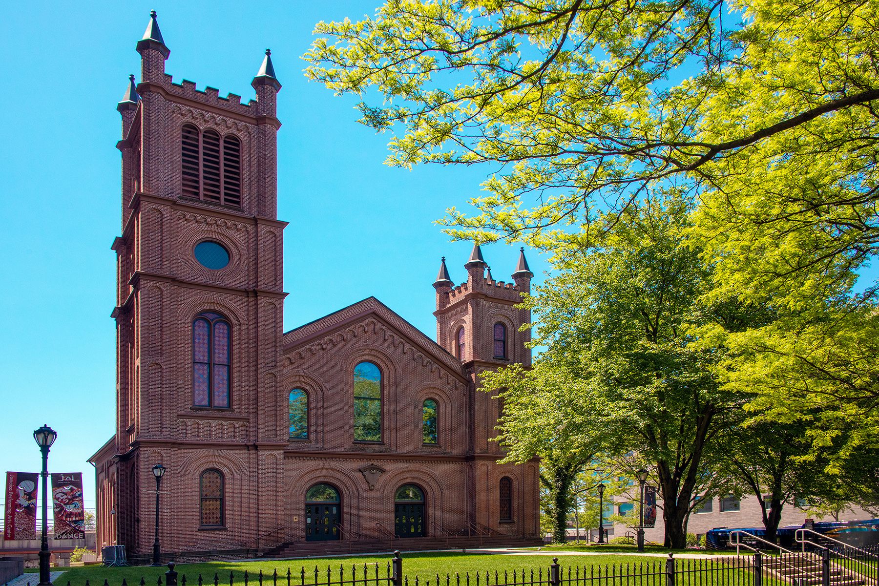 Jamaica Performing Arts Center brick building and grounds with green grass, trees and light blue sky
