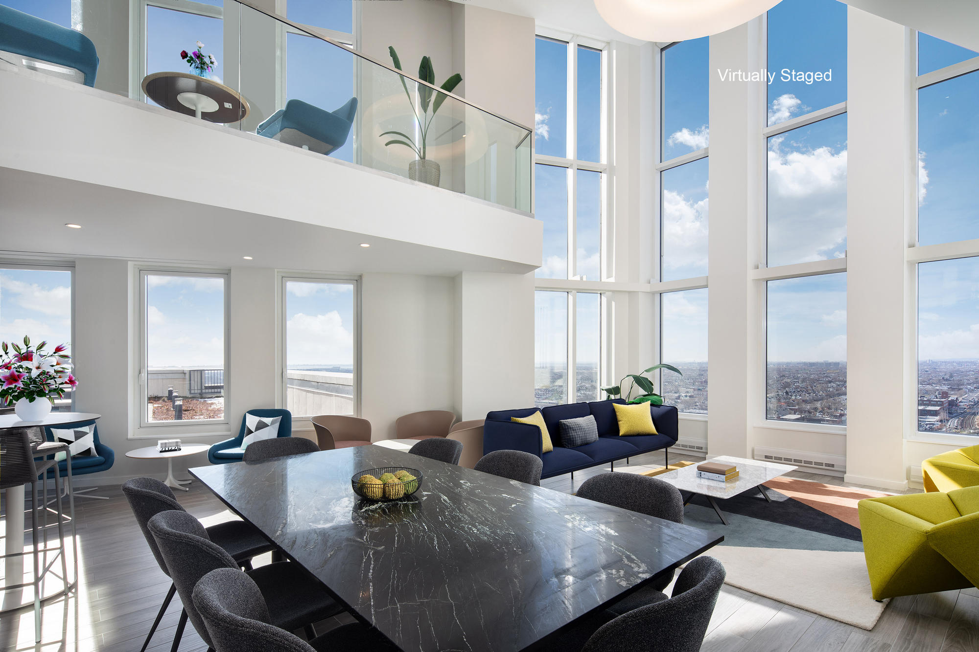 Bright Modern two floor lounge with conference table, coffee tables and seating, tall windows with city views and light wood floors